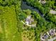 Stunning aerial view of a modern home with a private pool surrounded by lush greenery and a serene pond at 6115 Stonegate Run, Zionsville, IN 46077
