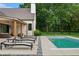 Backyard oasis showcasing a pool, sleek lounge chairs, lush landscaping, and a covered patio area at 6115 Stonegate Run, Zionsville, IN 46077