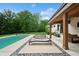 Relaxing backyard featuring a sparkling pool, sleek lounge chairs, a covered patio, and mature trees at 6115 Stonegate Run, Zionsville, IN 46077