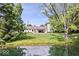 Scenic backyard with pond view of the house and green, lush landscaping at 6115 Stonegate Run, Zionsville, IN 46077