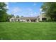 Large, green backyard with a modern home, covered patio, swimming pool, and mature trees on a sunny day at 6115 Stonegate Run, Zionsville, IN 46077