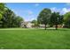 Expansive front yard with lush green grass and mature trees surrounding a beautiful, modern single-story home at 6115 Stonegate Run, Zionsville, IN 46077
