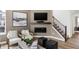 Well-lit living room featuring modern seating, stylish decor, a cozy fireplace, and a staircase leading upstairs at 6580 Halsey St, Zionsville, IN 46077