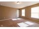 Neutral-colored bedroom showcasing plush carpet, a ceiling light, and bright natural light from dual windows at 6610 Aberdeen Dr, McCordsville, IN 46055