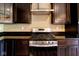 Well-equipped kitchen with stainless steel range, modern vent hood, granite counters, and dark wood cabinets at 6610 Aberdeen Dr, McCordsville, IN 46055