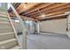 Unfinished basement with exposed wood ceiling, concrete floor, and white painted walls and stairs at 6741 Evanston Ave, Indianapolis, IN 46220