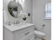 Updated bathroom with a white vanity, round mirror, and modern fixtures at 6741 Evanston Ave, Indianapolis, IN 46220