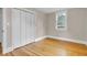 A bright bedroom features a window, closet, neutral walls, and beautiful hardwood floors at 6741 Evanston Ave, Indianapolis, IN 46220