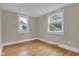 An empty bedroom is filled with light and features wood floors and two large windows at 6741 Evanston Ave, Indianapolis, IN 46220