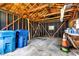 Interior of garage with exposed wood beams, black walls, concrete floor, and 2 blue trash cans at 6741 Evanston Ave, Indianapolis, IN 46220