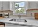Close-up of a kitchen sink and window with white cabinets and quartz countertops at 6741 Evanston Ave, Indianapolis, IN 46220