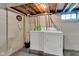 Basement laundry area with white washer and dryer, adjacent to utility area and exposed beams at 6741 Evanston Ave, Indianapolis, IN 46220