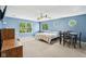 Light-filled bedroom featuring soft blue walls, neutral carpet, a ceiling fan and several windows with wooded exterior views at 829 Pioneer Woods Dr, Indianapolis, IN 46224