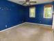 A blue bedroom with carpet and two windows with coverings and a ceiling fan at 8425 E 82Nd E St, Indianapolis, IN 46256