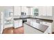 Modern kitchen with white cabinets, stainless steel appliances, an island, and hardwood floors is great for entertaining at 9643 Cypress Way, Carmel, IN 46032