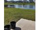 Landscaped backyard featuring a pond view, a black fence, and a cement porch with black planters at 10218 Arctic Edge Dr, Indianapolis, IN 46259