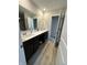 Bathroom featuring a double vanity with dark cabinets, a large mirror, and wood-look flooring at 10218 Arctic Edge Dr, Indianapolis, IN 46259