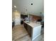 Open kitchen featuring island seating, a stainless steel dishwasher, wood-look floors, and seamless access to living areas at 10218 Arctic Edge Dr, Indianapolis, IN 46259