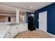 View of the kitchen with a stainless steel double sink and black refrigerator on wood floor with blue accent wall at 11074 Galley Way, Fishers, IN 46040