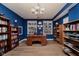Bright office with blue walls, built-in bookshelves, wooden desk and chair, recessed lighting and wood floors at 11074 Galley Way, Fishers, IN 46040