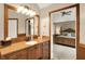 Bathroom with wood cabinets, mirror, lighting, and view into the bedroom at 12450 Petalon Trce, Fishers, IN 46037