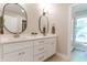 Double sink vanity with white cabinets, modern faucets, and oval mirrors in the updated bathroom at 14407 Bryn Mawr Dr, Fishers, IN 46038