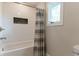 Bathtub with white subway tile surround, dark tile niche and grey striped shower curtain by window in updated bathroom at 14407 Bryn Mawr Dr, Fishers, IN 46038