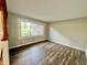 Bedroom with modern wood flooring and natural light from a large window with green lawn view at 15841 E 265 N, Columbus, IN 47203