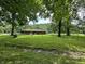 Spacious backyard showcasing a well-maintained lawn, mature trees, and a charming ranch-style home at 1980 S Arthur Rd, Paragon, IN 46166
