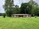 Charming brick ranch home with a well-manicured lawn, mature trees, and classic black shutters at 1980 S Arthur Rd, Paragon, IN 46166