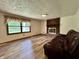 Bright living room featuring wood floors, a cozy brick fireplace, and a comfortable leather sofa at 1980 S Arthur Rd, Paragon, IN 46166