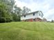 View of the two-story home with white siding, red brick, and green landscaping on a hill at 2615 Alexandria Pike, Anderson, IN 46012