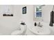 A clean bathroom with a toilet, sink, mirror, and decorative art at 2720 Guilford Ave, Indianapolis, IN 46205