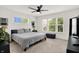 A bedroom with neutral carpet, a queen-sized bed, two windows, and a black ceiling fan at 2720 Guilford Ave, Indianapolis, IN 46205