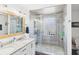 Modern bathroom featuring a dual sink vanity, large mirror, and walk-in shower with glass block window at 4511 W 300 S, Anderson, IN 46011