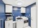 Laundry room featuring stylish blue walls, front load machines, cabinet storage, and light-colored floors at 4511 W 300 S, Anderson, IN 46011