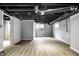 Unfinished basement featuring white brick walls, dark painted ceiling, and light colored woodgrain floors at 4904 N Washington Blvd, Indianapolis, IN 46205