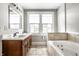 Bright bathroom features a double vanity, large window, and a soaking tub with tile surround at 4904 N Washington Blvd, Indianapolis, IN 46205