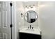 Modern bathroom features a black vanity, quartz countertop, round mirror, and stylish fixtures at 5759 Columbia S Cir, Greenwood, IN 46142