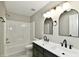 Modern bathroom featuring double sinks, sleek black hardware, arched mirrors, and a shower-tub combo at 5759 Columbia S Cir, Greenwood, IN 46142