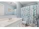 Well-lit bathroom featuring a single sink vanity, toilet and blue floral shower curtain at 6120 E Southport Rd, Indianapolis, IN 46237