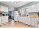 Bright kitchen with tile flooring, white cabinets and appliances, and a window over the sink at 6120 E Southport Rd, Indianapolis, IN 46237