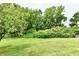 Lush backyard featuring manicured lawn, mature trees, and established shrubbery at 6851 Azalea Dr, Indianapolis, IN 46214