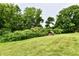 Backyard view of a shed nestled among mature trees, shrubs, and manicured lawn at 6851 Azalea Dr, Indianapolis, IN 46214