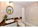 Charming bathroom features decorative mirror, pedestal sink, and tub with white tile at 6851 Azalea Dr, Indianapolis, IN 46214