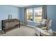 Bedroom with blue walls, crib, white chair, curtains and a view of the neighborhood at 843 Garrow Dr, Westfield, IN 46074