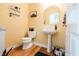 Cozy powder room featuring a pedestal sink, decorative mirror, and hardwood floors at 8785 W 100 N, Anderson, IN 46011