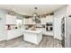 A bright, white kitchen features an island, stainless steel appliances, pot rack, and wood grain floors at 9053 Fitzgerald Dr, Indianapolis, IN 46239