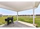 This covered patio includes a grill and a view of the grassy backyard and community pond at 9053 Fitzgerald Dr, Indianapolis, IN 46239