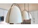 Modern white pendant lights hang above a kitchen, offering a stylish and bright focal point, complementing the sleek design at 925 Veterans Way # 101, Carmel, IN 46032